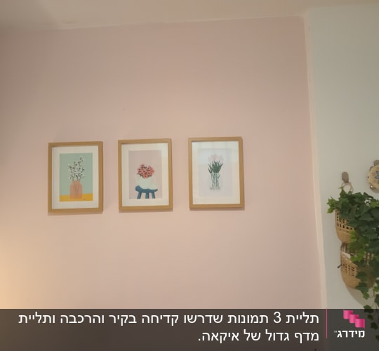 תליית שלוש תמונות ממוסגרות בשורה על קיר סלון